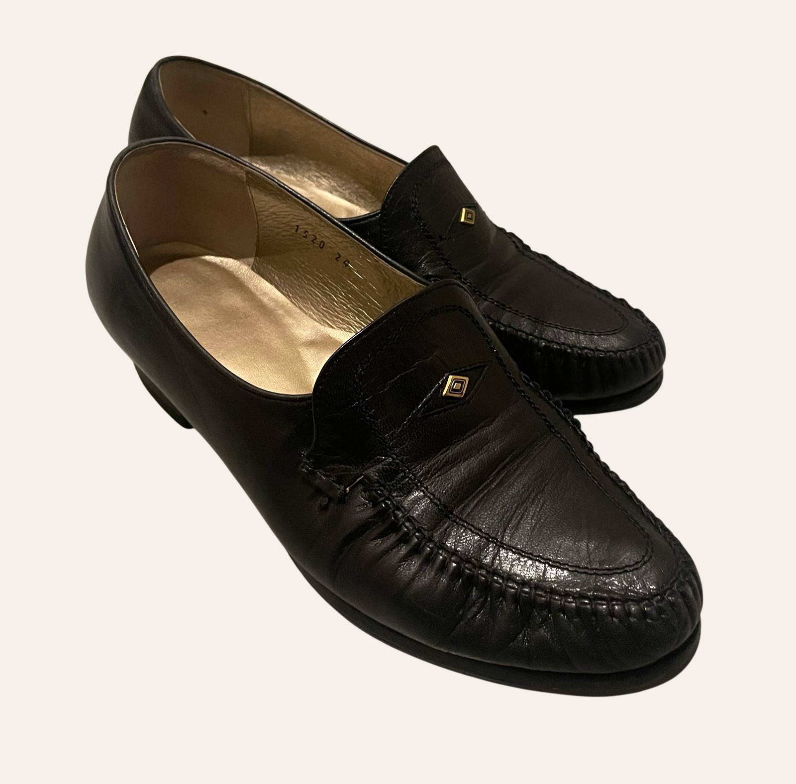 A pair of worn black leather loafers photographed flat