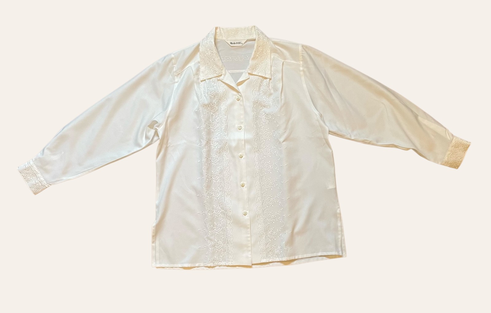An off-white vintage blouse photographed flat on a plain background