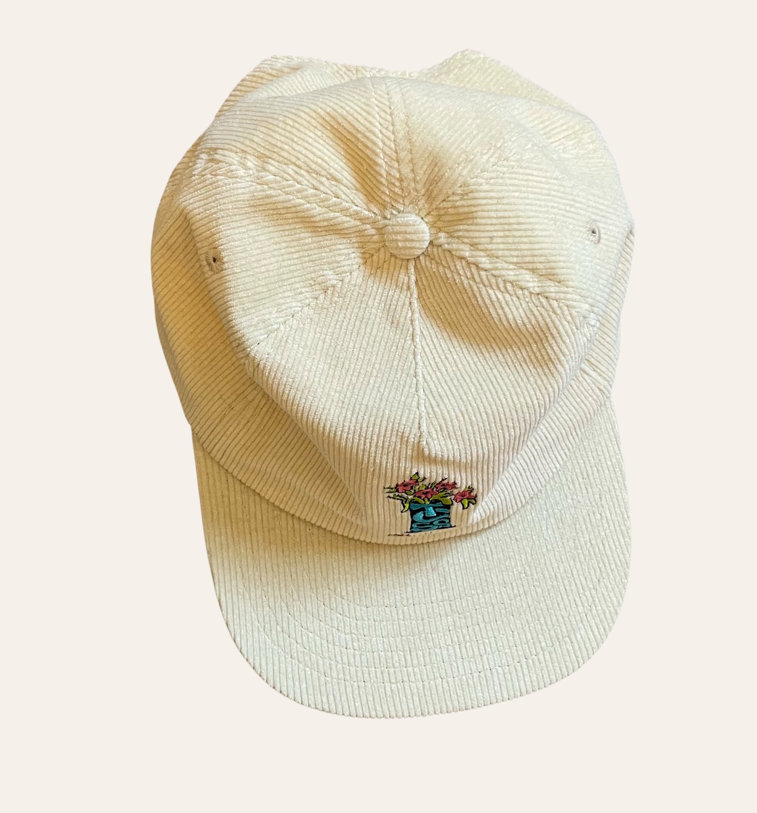 A cream corduroy cap photographed flat